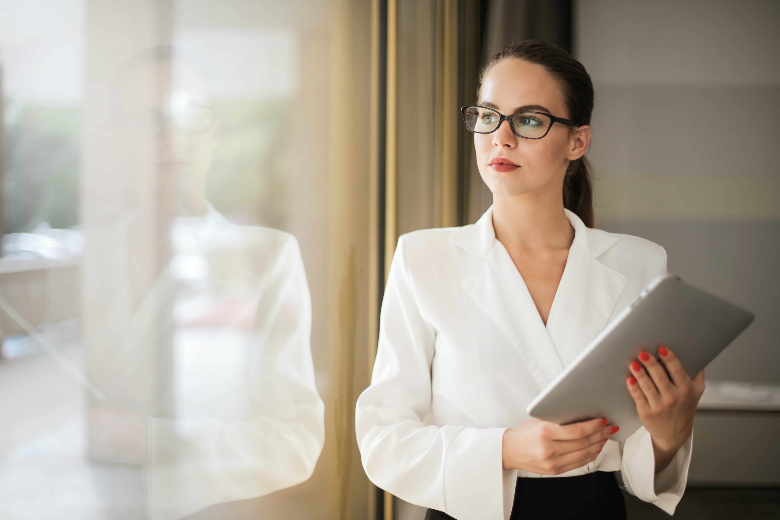 photo-of-woman-in-white-top-and-glasses-holding-a-tablet